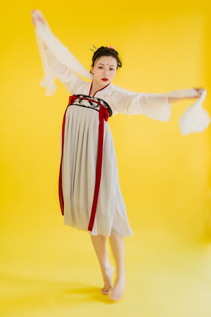 Asian woman gracefully posing in traditional Hanfu against a vibrant yellow background.